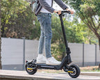 A young man wearing a helmet is riding a Todimart-X5s electric scooter: a black Todimart-X5s electric scooter (equipped with durable tires) – casual attire, outdoor setting – perfect for city commuting